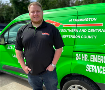 Servpro employee standing in front of a green Servpro truck.